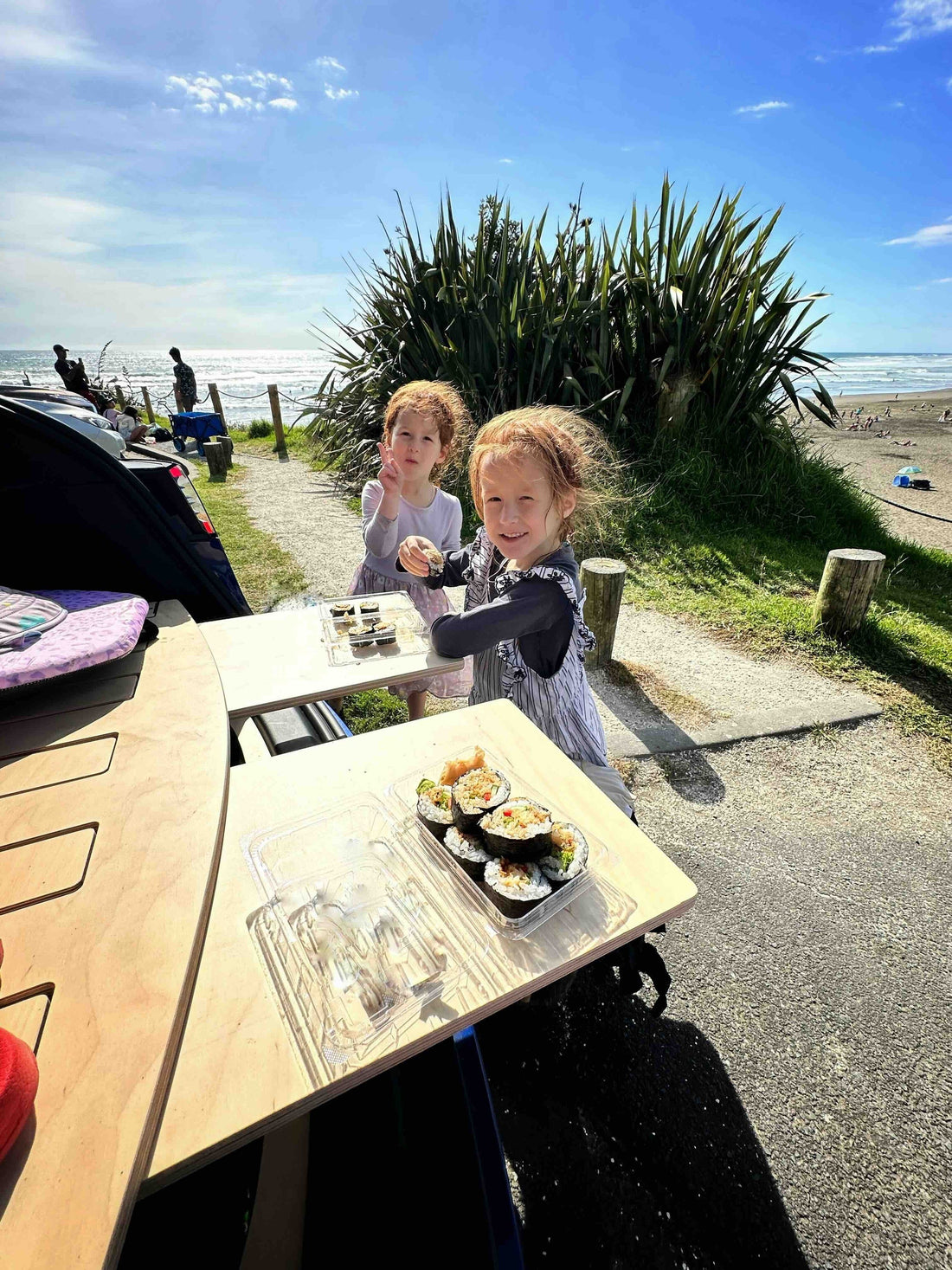 Children enjoying a meal using the Tesla Model Y trunk bed tables during a family camping trip in Australia's bushland.