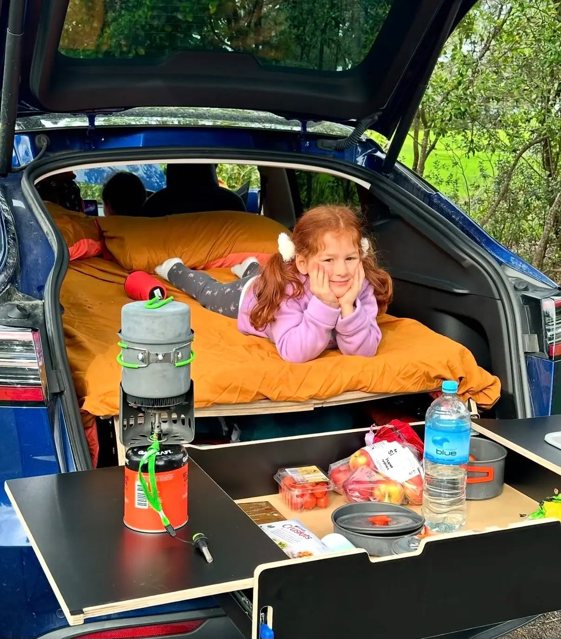 Child resting on a Teraglide camping platform in a car, with the drawer open during camping