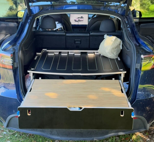 Tesla Model Y with Teraglide PRO platform bed set up in a scenic NZ location, showing drawer and bamboo table