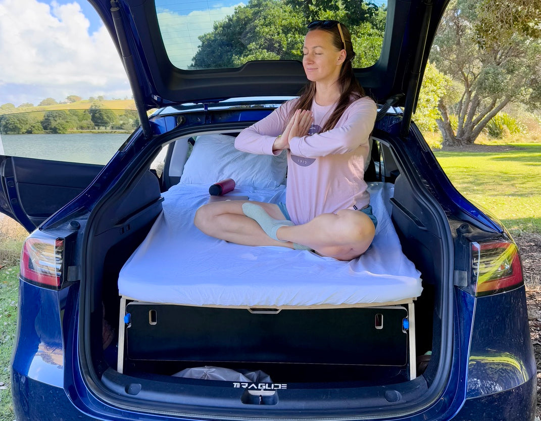 Woman relaxing inside an open SUV trunk with a Teraglide platform bed during a peaceful solo car camping trip