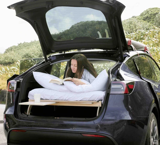 Tesla Y parked in nature with a Teraglide car camping platform set up as a flat bed inside, showing a calm, organised sleeping space for stress-free road travel.