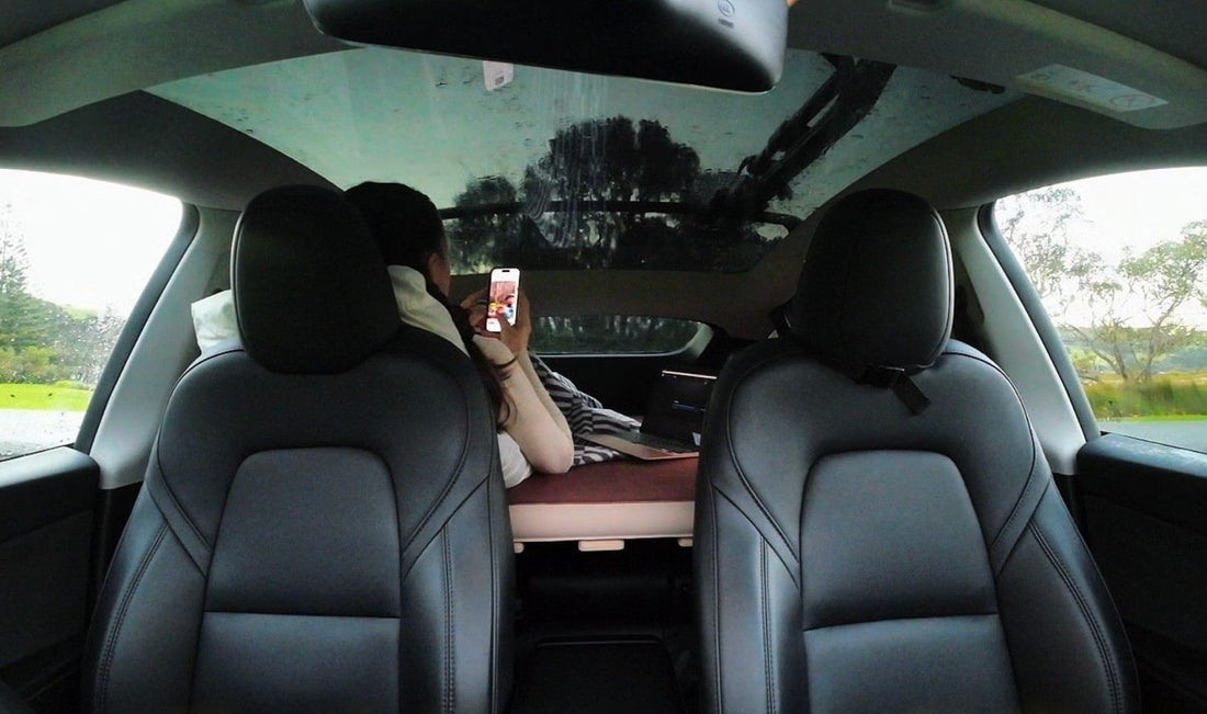 Working on a laptop inside a Tesla Model Y converted into a mini camper with a Teraglide platform