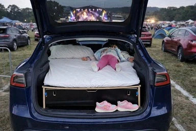 Car with a Teraglide camping platform set up in the trunk, parked at a music festival campsite, ready for a comfortable night’s sleep