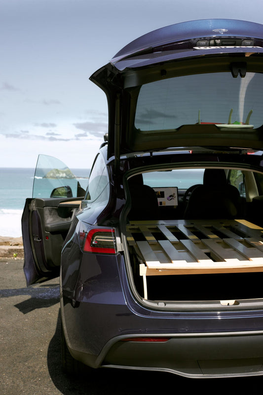 Car camping platform fully unfolded inside SUV showing dry, flat sleeping surface with storage below