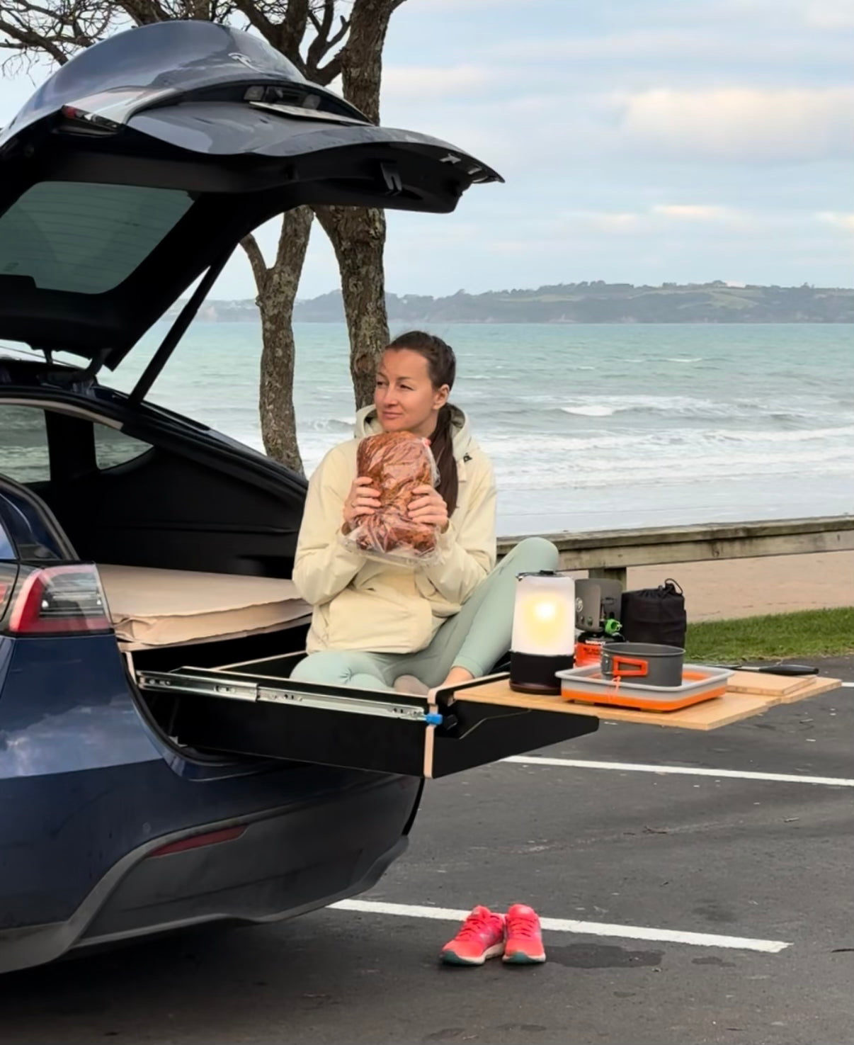 Tesla Y with open tailgate showing full camping setup—bed, storage, and lights