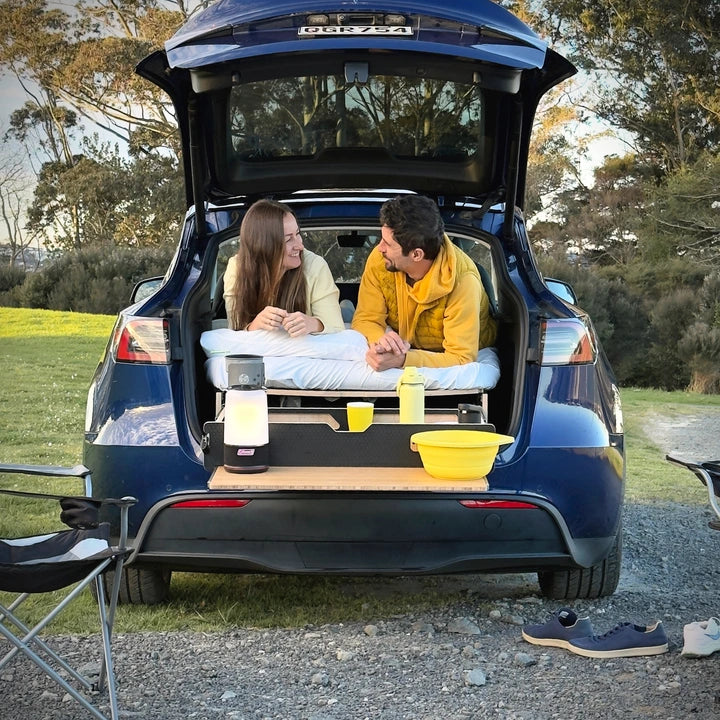 Couple lying on the flat Teraglide PRO bed in a Tesla Model Y with the drawer pulled out